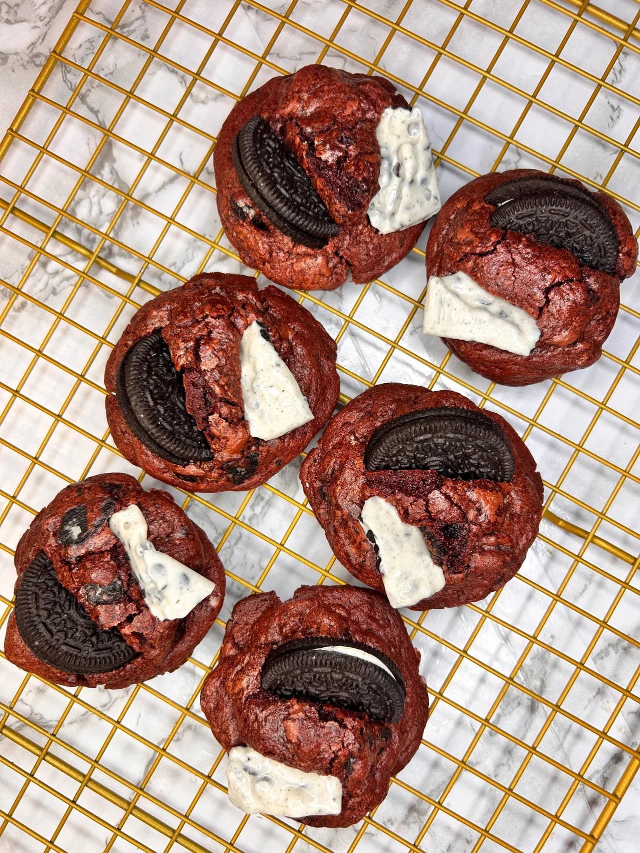 Red velvet cookies with Oreo pieces and white chocolate on a golden cooling rack
